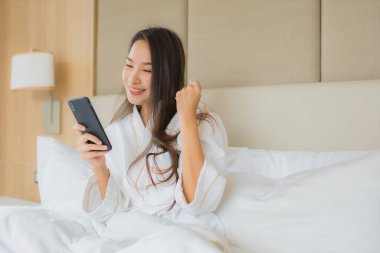 Yatak odasının içinde akıllı cep telefonlu güzel Asyalı kadın portresi.