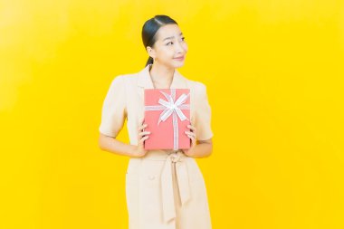 Güzel bir Asyalı kadının portresi. Arka planda kırmızı hediye kutusuyla gülümsüyor.