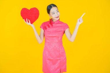 Portre güzel Asyalı genç kadın gülümsüyor kalp yastığı şeklinde renk arkaplan
