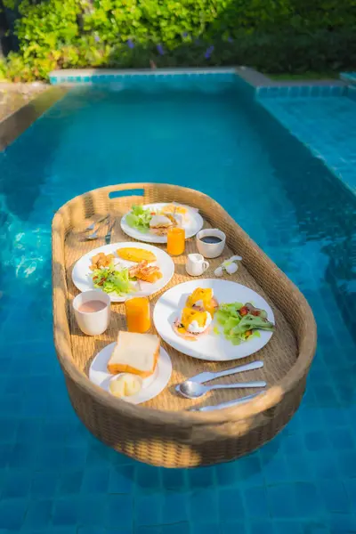 Floating breakfast around outdoor swimming pool in hotel resort