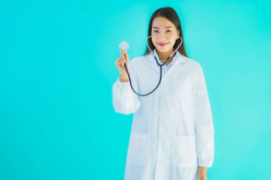 Klinikte ya da mavi izole edilmiş arka planda hastanede kullanmak üzere steteskoplu güzel Asyalı genç doktor kadın portresi.