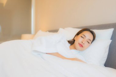Asyalı güzel bir kadının portresi. Gülümse. Yatak odasında rahatla.
