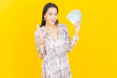 Asyalı güzel bir kadının portresi. Renkli arka planda bol para ve parayla gülümsüyor.