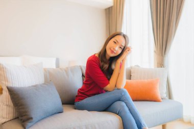 Güzel bir Asyalı kadın portresi. Yatak odasındaki kanepede rahatla. Gülümse.