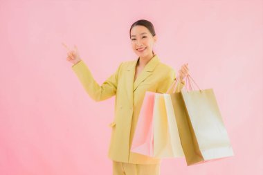 Renkli arka planda alışveriş çantası taşıyan güzel Asyalı iş kadını portresi.