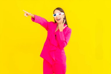 Güzel bir Asyalı kadın, sarı izole edilmiş arka plandaki film için 3D gözlük takıyor.