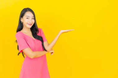 Asyalı güzel bir kadının portresi. Sarı arka planda hareketli gülümsüyor.