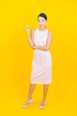 Asyalı güzel bir kadının portresi. Sarı arka planda hareketli gülümsüyor.