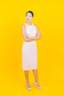 Asyalı güzel bir kadının portresi. Sarı arka planda hareketli gülümsüyor.