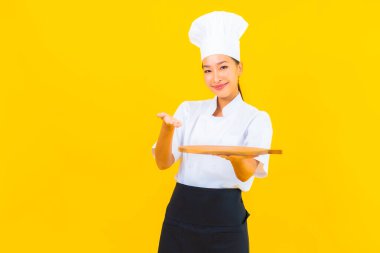 Sarı izole arka planda tahta kesim tahtasıyla güzel bir Asyalı kadın portresi.