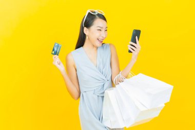 Portre güzel Asyalı kadın tebessümü ile renk arka planında alışveriş torbası