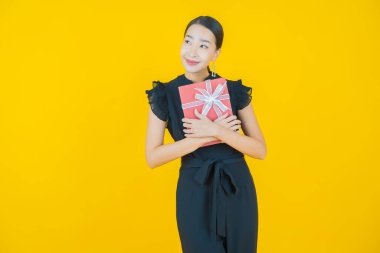 Güzel bir Asyalı kadının portresi. Arka planda kırmızı hediye kutusuyla gülümsüyor.