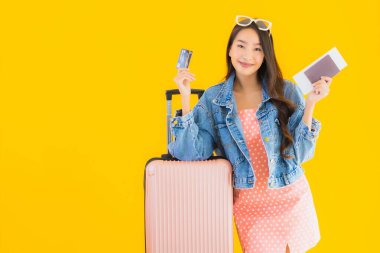 Çantalı güzel Asyalı kadın. Pasaportu ve sarı izole bir arka planda bilet.