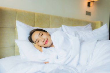 Güzel bir portre genç Asyalı kadın yatak odasında yastık ve battaniyeyle yatakta uyuyor.