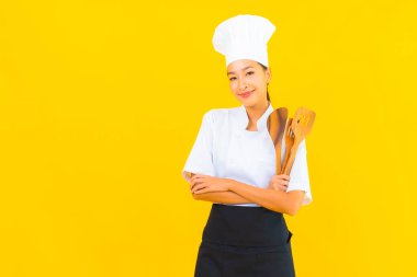 Sarı izole arkaplanda spatulası olan güzel, genç Asyalı şef kadın portresi.