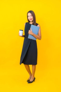 Sarı arka planda dizüstü bilgisayarı olan güzel Asyalı iş kadını portresi