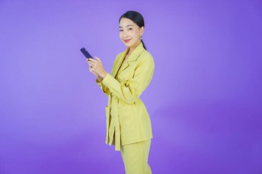 Renkli arka planda akıllı cep telefonuyla güzel Asyalı kadın gülümsemesi