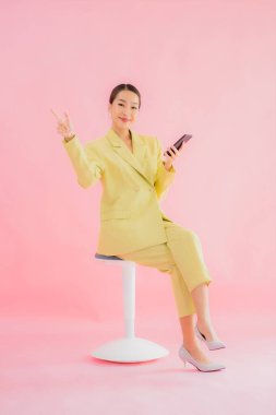 Güzel Asyalı iş kadını portresi. Arka planda kahve fincanı ve akıllı cep telefonu kullanıyor.