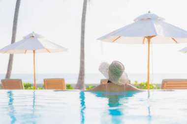 Güzel bir Asyalı kadın portresi. Tatil gezisinde deniz manzaralı açık havuz etrafında rahatça yüzebiliyor.