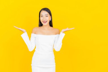 Portre güzel genç iş kadını gülümseyen ve eylem sarı arka planlı Asyalı kadın