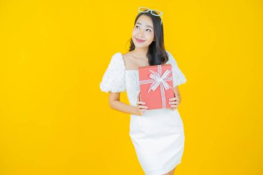 Güzel bir Asyalı kadının portresi. Arka planda kırmızı hediye kutusuyla gülümsüyor.