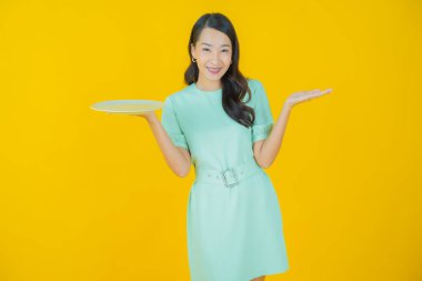 Güzel Asyalı bir kadının portresi. Arka planda boş tabak tabağıyla gülümsüyor.