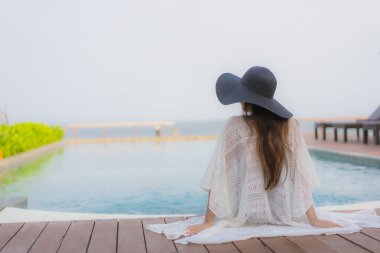 Asyalı genç bir kadının portresi mutlu bir gülümseme otel tatil beldesinde yüzme havuzunda rahatlamak