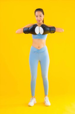 Güzel bir Asyalı kadın portresi, sarı izole edilmiş arka planda boks yaparken spor giyer.