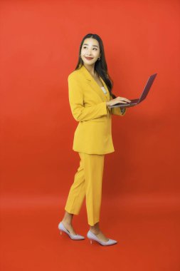 Portre güzel genç iş kadını Asyalı kadın kırmızı arka planda bilgisayar bilgisayarı kullanıyor