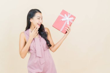 Güzel bir Asyalı kadının portresi. Arka planda kırmızı hediye kutusuyla gülümsüyor.
