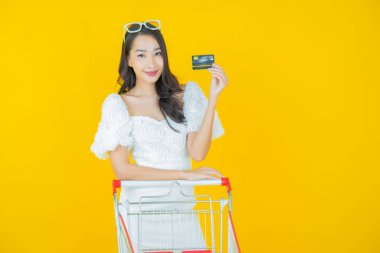 Renkli arka planda süpermarketten alınmış market sepetiyle gülümseyen güzel Asyalı kadın portresi.