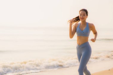 Portre sporu genç Asyalı kadın egzersiz hazırlıyor ya da sağlık için okyanusta koşuyor.