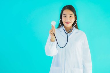 Klinikte ya da mavi izole edilmiş arka planda hastanede kullanmak üzere steteskoplu güzel Asyalı genç doktor kadın portresi.