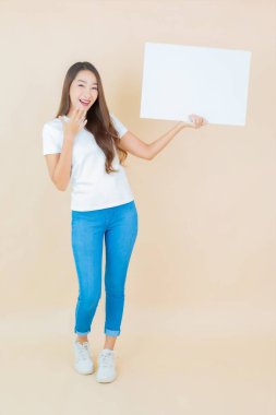 Güzel bir Asyalı kadın portresi. Krem arka planda boş beyaz ilan panosu kağıdı gösteriyor.