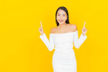 Portre güzel genç iş kadını gülümseyen ve eylem sarı arka planlı Asyalı kadın