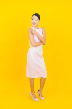 Asyalı güzel bir kadının portresi. Sarı arka planda hareketli gülümsüyor.