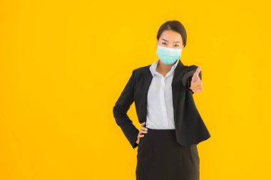 Güzel genç iş kadını portresi Korunmak için maske takıyor 19 koronavirüs sarı izole arka planda