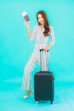 Güzel Asyalı bir kadının portresi. Bavul pasaportu ve biniş kartı mavi arka planda seyahat için hazır.