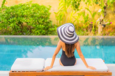 Güzel bir Asyalı kadının portresi tatil için yüzme havuzunda rahatlıyor.