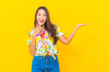 Güzel bir Asyalı kadın Tayland 'daki sonkran festivali için sarı arka planda renkli bir gömlek giyiyor.