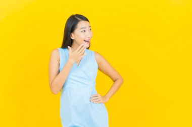 Asyalı güzel bir kadının portresi. Sarı arka planda hareketli gülümsüyor.