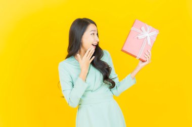 Güzel bir Asyalı kadının portresi. Arka planda kırmızı hediye kutusuyla gülümsüyor.