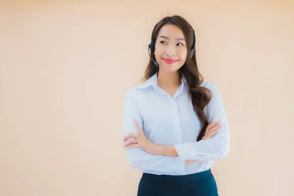 肖像画美しいです若いアジアのビジネス女性とともにヘッドフォンのためのコールセンター上の色隔離された背景 — ストック写真