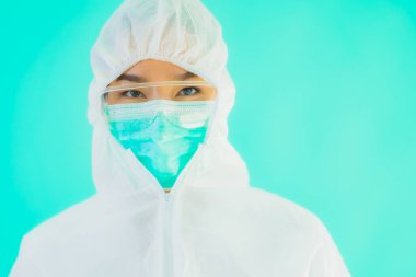 Güzel, genç Asyalı doktor kadın portre. Koronavirüsten ya da mavi arka planda kovid19 'dan korunmak için ppe ya da kişisel koruyucu ekipman takıyor.