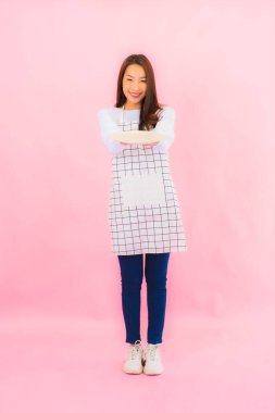 Portrait beautiful young asian woman in kitchen wear with apron on pink isolated background