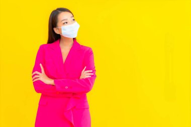 Güzel bir Asyalı kadın koronavirüsü korumak için maske takıyor ya da sarı arka planda 19 numara giyiyor.