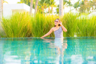 Güzel bir Asyalı kadın portresi. Rahatlayın, gülümseyin. Tatil için oteldeki yüzme havuzunun keyfini çıkarın.