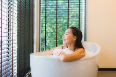 Güzel bir Asyalı kadın portresi mutlu bir gülümseme rahatla banyo küvetinde banyo yap.