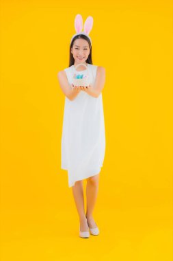 Sarı izole edilmiş arka planda paskalya yumurtası olan güzel Asyalı kadın portresi.