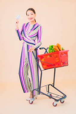 Marketten aldığı alışveriş sepetiyle güzel bir Asyalı kadının portresi. Renkli, izole arka plan.